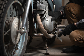 A motorcycle mechanic with a wrench in hand close up.