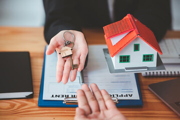 Real estate agent with house plans and keys in hand.