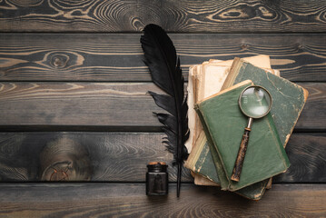 Stack of old books, quill pen and magnifying glass on the writer table flat lay background with copy space. Education. - obrazy, fototapety, plakaty