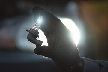 A light bulb of car headlight in auto electrician hand close up.