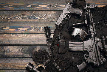 Airsoft weapons and equipment on the wooden flat lay background with copy space.