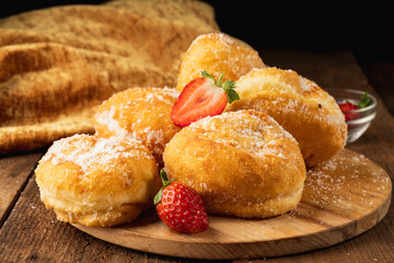 Hawaiian malasada donuts on a wooden plate. Wooden table.