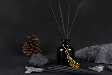 luxury aroma scent reed diffuser black glass bottle is on black table with rocks and pine cone to creat romantic and relax ambient in bedroom with black cement wall background on happy valentine day