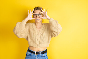 Young beautiful woman wearing casual sweater over isolated yellow background Trying to open eyes with fingers, sleepy and tired for morning fatigue