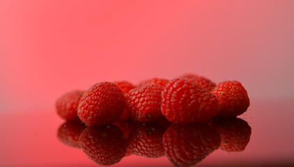 Raspberry fresh fruits photographed against red background. Raspberries food photography. Details of this tasty forest fruits.