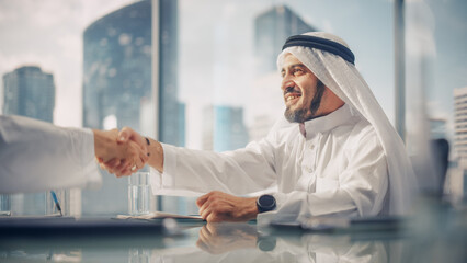 Smiling Emirati Businessman in White Traditional Kandura Sitting in Office with Business Partners....