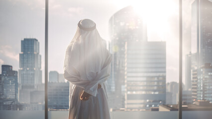 Successful Muslim Businessman in Traditional White Outfit Standing in His Modern Office Looking out...