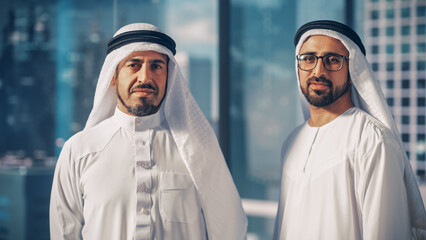 Portrait of Two Successful Muslim Businessmen in Traditional Outfits Gently Smiling, Wearing White...
