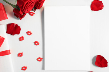 Blank template with copy space on the table, top view. Holiday card mockup with list for congratulations with red roses bouquet and gifts, flat lay.