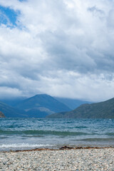 Fototapeta na wymiar View of the Lake in the mountains in spring. Patagonian Coast Lake. Waves on the coast. Peninsula. Vertical Panoramic View. Vertical photo. 