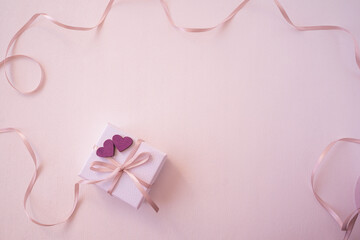 Gift box with hearts and ribbon for a loved one for Valentine's Day. Free space for inscription on a pink background