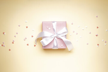 Gift box for Valentine's Day and confetti on yellow background. Flat lay.
