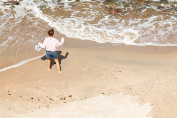 Little happy girl dance on the beach near shore