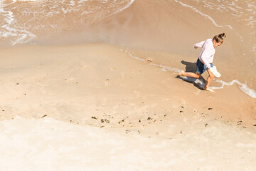 Little girl runs on the beach near shore water