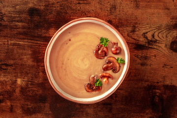 Mushroom cream soup, overhead shot on a dark rustic wooden background