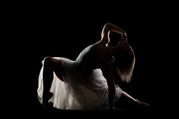 ballerina with a white dress and black top posing on black background. side lit silhouette. © Nikola Spasenoski