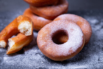 Donuts with powdered sugar. Traditional donuts in the shape of a ring fried in oil, on a black...