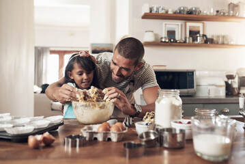 Family love is messy. Shot of a father teaching his daughter how to bake in the kitchen at home.