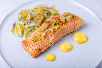 Fried salmon with fennel and orange salad with hollandaise sauce. Garnished with leeks. French dish. Close-up.