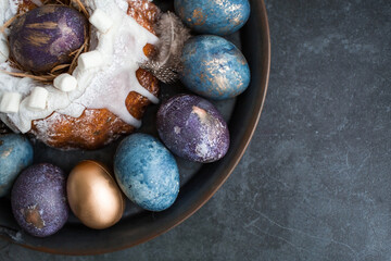 Easter card with a copy of the place for the text. Purple, blue and golden eggs with a cake on a dark background. The purple hue trend of 2022 is very peri. Natural dye karkade tea. Top view.