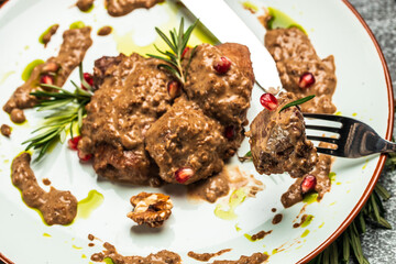 White plate of pork medallions with walnut sauce. Georgian cuisine. Ketogenic diet food. banner, menu, recipe place for text, top view