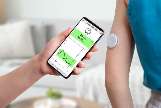 Measurement of blood glucose with the help of mobile app and sensor. Hand brings the phone closer to the sensor located on the child's hand concept