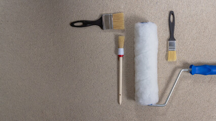 Roller for paint and brushes for painting walls on a gray concrete background