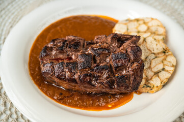 Deer meat steak, plum spicy sauce, dumpling on plate, on white table, closeup.