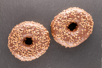 Two sweet chocolate donuts on a slate rock, macro, top view.