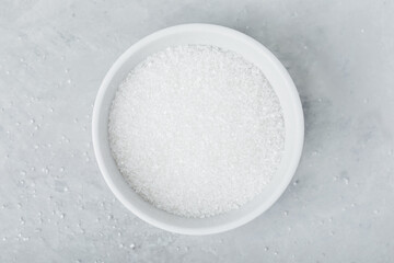 White sugar in bowl on gray stone background