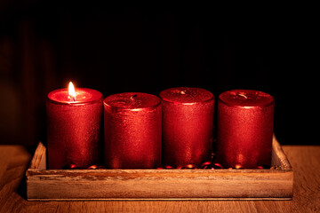 First lit red advent candle, december christmas tradition isolated on black