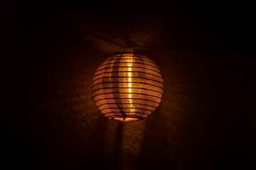 Orange ball glowing fairy light Japanese lantern isolated on black