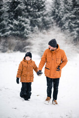 Fototapeta na wymiar Happy father walking with son at snowy park