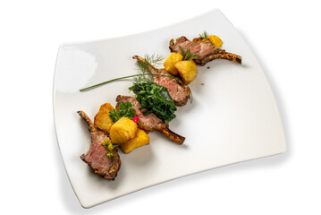 Roasted lamb chops with potatoes, spinach and herbs on white plate isolated on white © framarzo