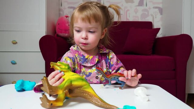 beautiful baby plays in her room with toy dinosaurs