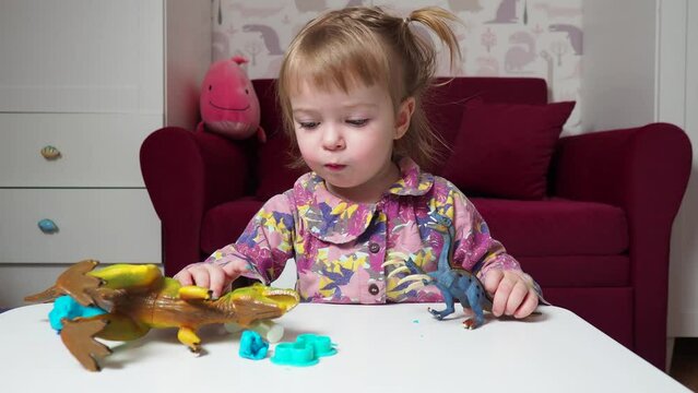 beautiful baby plays in her room with toy dinosaurs