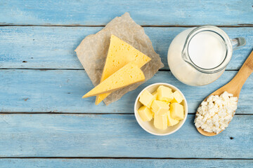 dairy products, cheese, butter, cottage cheese, milk on a blue wooden table, space for text