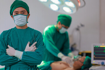 Fototapeta na wymiar Portrait of Asian male surgeon with team of doctors on background in operation room.
