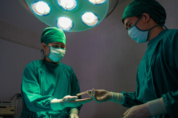 Asian male doctor performing surgery in operation room.