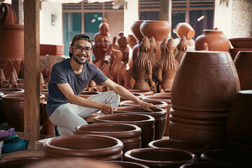 man in glasses holding pottery to sell at craft stall