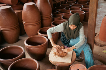 Muslim girl in hijab sitting processing clay into pottery