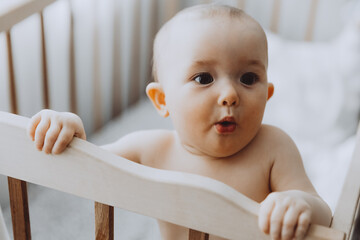 Candid shot of six month old infant baby  standing in the crib holding on to the side