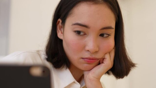 Upset Asian woman studying distance learning on the tablet at home