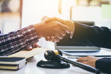 Young lawyer and a client shake hands after agreeing to legal work.