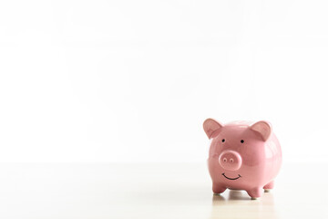 Piggybank of pink pigs placed on a wooden table. The concept for Finance, Banking, Savings, Investing, Marketing, Close up. Copy space on left for design or text. Nobody and white background