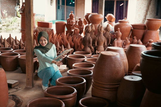 veiled woman using clipboard at ceramic pottery stall