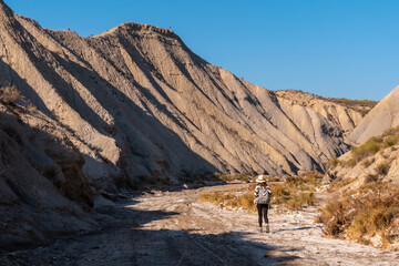 A young hiker with a backpack in the desert of Tabernas, Almería province, Andalusia. On a trek in the Rambla del Infierno