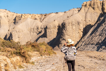 A young hiker with backpack and straw hat in the desert of Tabernas, Almería province, Andalusia....