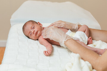 Physiotherapist performing a clavicle and first rib assessment on a newborn baby in a medical center.