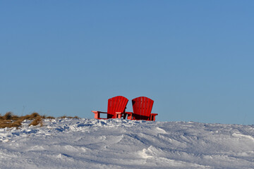 Winter scene of two red chairs sitting on a snow covered hill